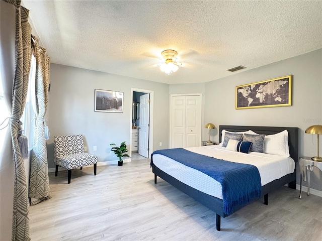 bedroom featuring ceiling fan, connected bathroom, a textured ceiling, a closet, and light wood-type flooring