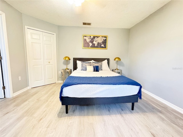 bedroom with light hardwood / wood-style floors, a closet, and a textured ceiling