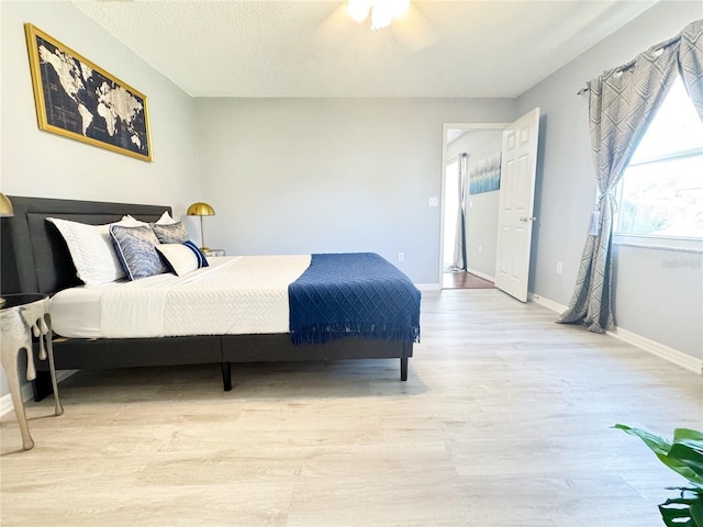 bedroom with ceiling fan, a textured ceiling, and light wood-type flooring