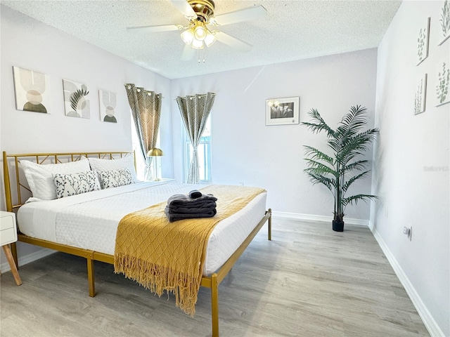 bedroom featuring ceiling fan, hardwood / wood-style floors, and a textured ceiling