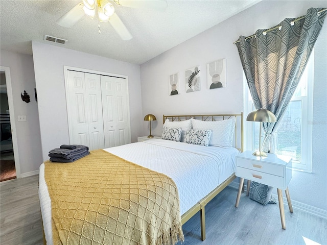 bedroom featuring ceiling fan, wood-type flooring, a closet, and a textured ceiling