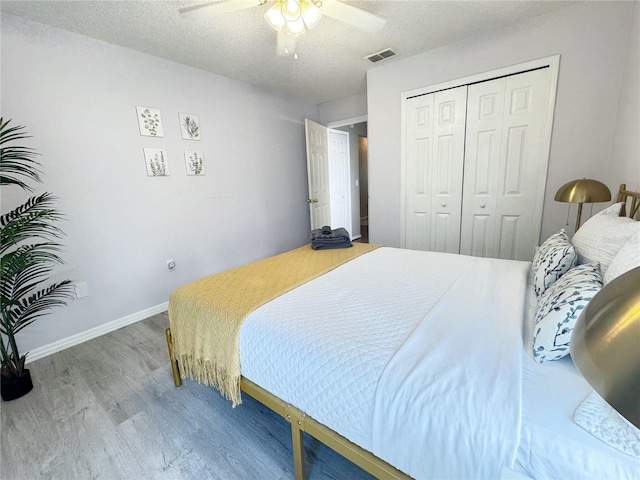 bedroom featuring ceiling fan, a closet, wood-type flooring, and a textured ceiling