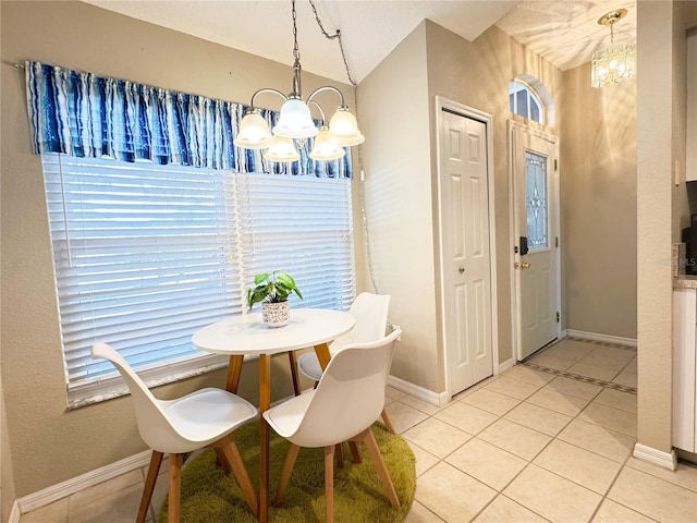 tiled dining space featuring a notable chandelier and vaulted ceiling