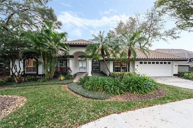 mediterranean / spanish home featuring a front yard and a garage