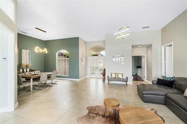 living room featuring french doors, light tile patterned flooring, and a notable chandelier