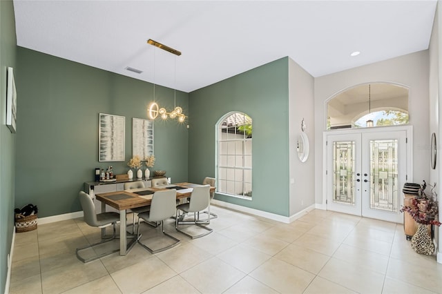 tiled dining area featuring an inviting chandelier and french doors