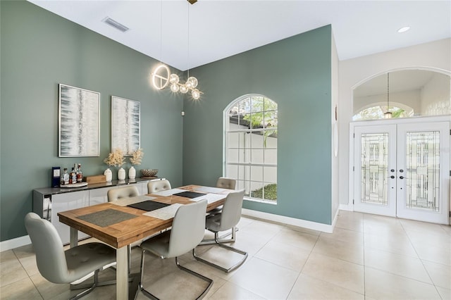 dining space with a notable chandelier, light tile patterned flooring, and french doors