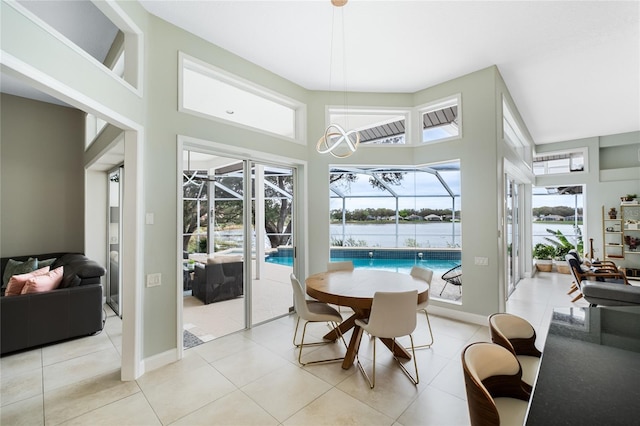 dining space with a water view, light tile patterned floors, and a towering ceiling