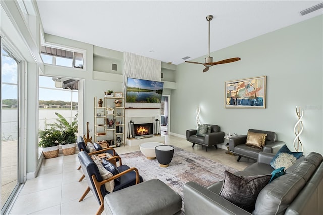 tiled living room with ceiling fan and a fireplace