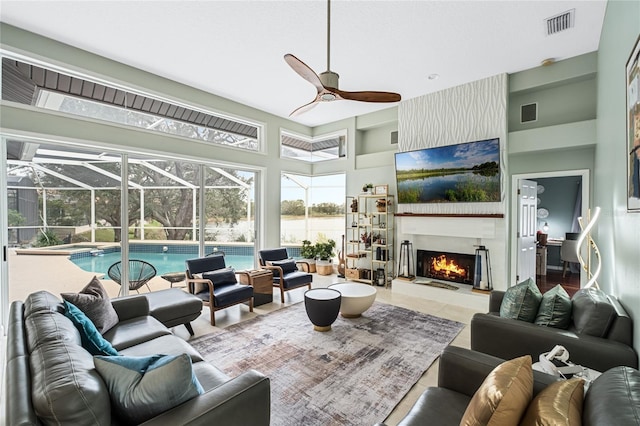 tiled living room featuring a large fireplace, a towering ceiling, and ceiling fan