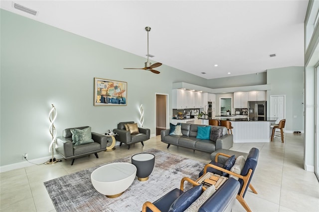 tiled living room featuring ceiling fan and a high ceiling