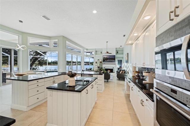 kitchen featuring a center island, pendant lighting, stainless steel appliances, and light tile patterned floors