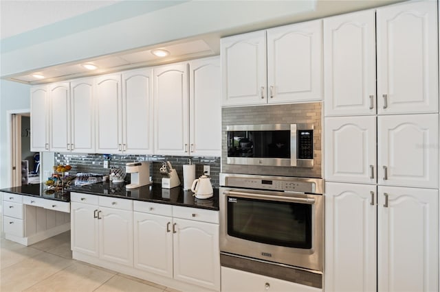 kitchen with light tile patterned floors, tasteful backsplash, stainless steel appliances, and white cabinetry