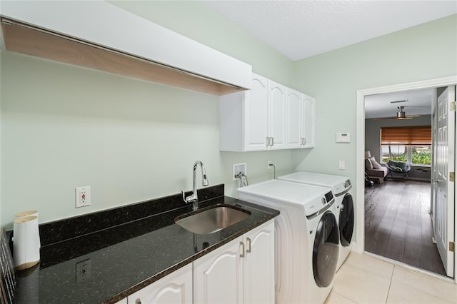 washroom featuring light tile patterned floors, sink, separate washer and dryer, a textured ceiling, and cabinets