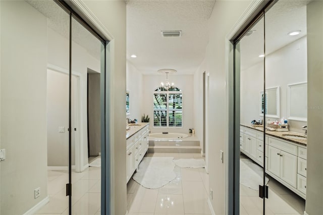 bathroom with vanity, a relaxing tiled tub, a textured ceiling, and tile patterned floors