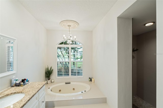 bathroom with a textured ceiling, independent shower and bath, vanity, and a notable chandelier