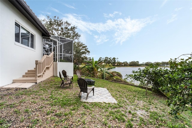 view of yard with a patio area, a water view, a lanai, and a fire pit