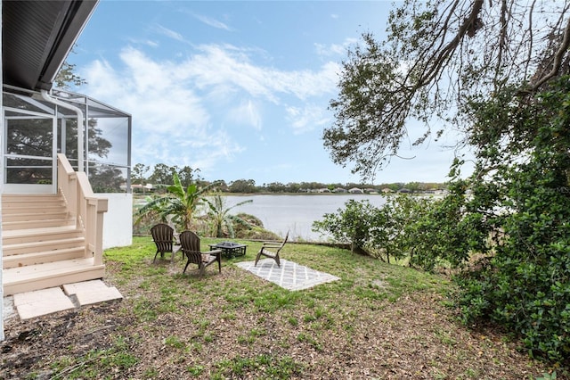 view of yard with an outdoor fire pit, a water view, and a lanai