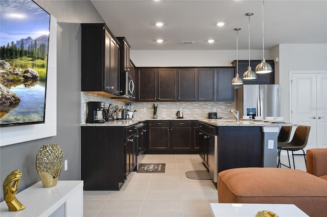 kitchen featuring light tile patterned flooring, a kitchen island, a breakfast bar area, hanging light fixtures, and stainless steel appliances