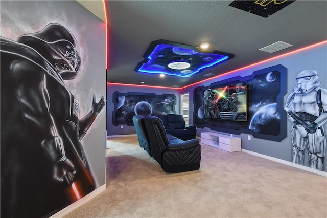 home theater room with a raised ceiling, carpet floors, and a textured ceiling