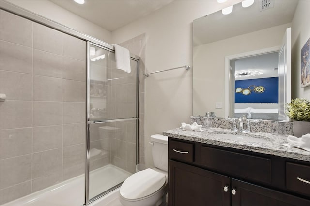 bathroom featuring vanity, a shower with shower door, and toilet