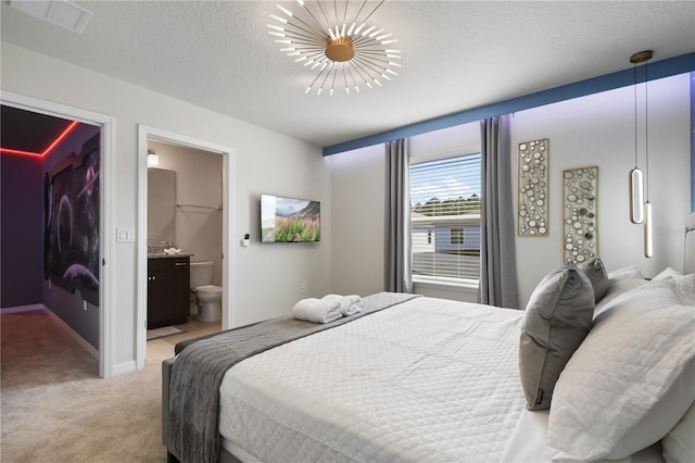 carpeted bedroom with ensuite bath and a textured ceiling