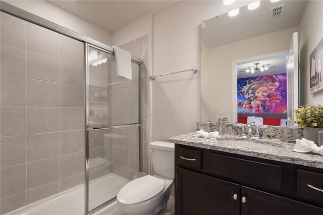 bathroom with a shower with door, vanity, and toilet