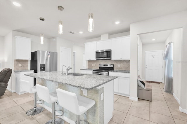 kitchen featuring sink, white cabinetry, a center island with sink, pendant lighting, and stainless steel appliances