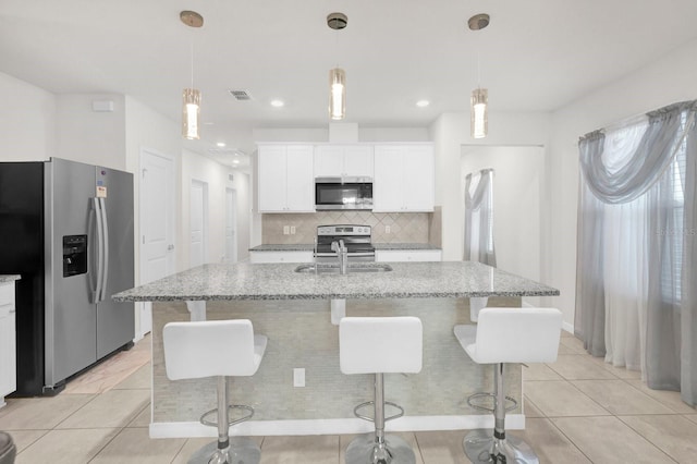 kitchen with sink, appliances with stainless steel finishes, a kitchen island with sink, hanging light fixtures, and white cabinets