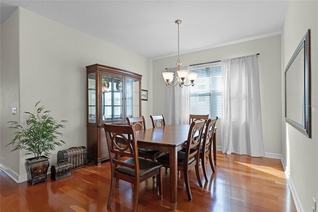 dining area featuring dark wood-type flooring and an inviting chandelier