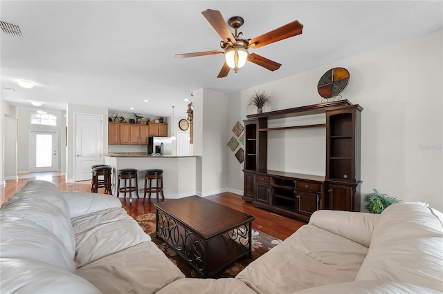 living room featuring dark wood-type flooring and ceiling fan