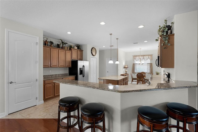 kitchen featuring a kitchen island, appliances with stainless steel finishes, decorative light fixtures, a kitchen breakfast bar, and kitchen peninsula