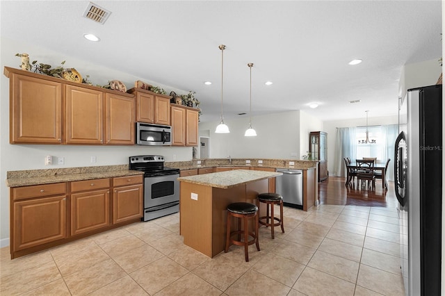 kitchen with hanging light fixtures, stainless steel appliances, kitchen peninsula, and a kitchen bar