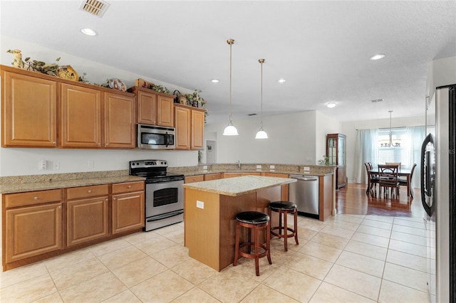 kitchen featuring stainless steel appliances, a kitchen island, a breakfast bar, and hanging light fixtures