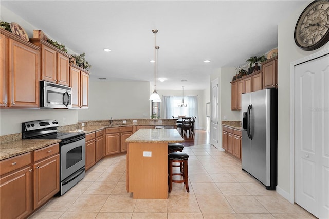 kitchen with a kitchen bar, light tile patterned floors, kitchen peninsula, a kitchen island, and stainless steel appliances