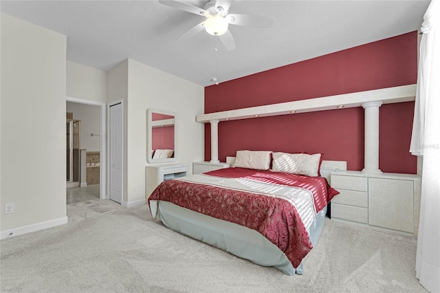 bedroom featuring ornate columns, ensuite bathroom, light colored carpet, and ceiling fan