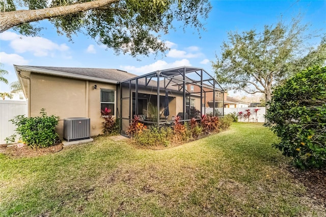 rear view of house featuring cooling unit, a yard, and a lanai