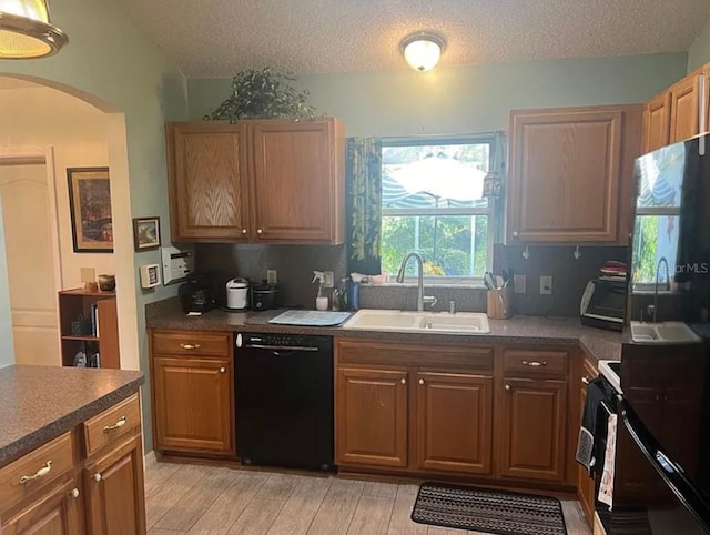 kitchen featuring sink, black appliances, light hardwood / wood-style floors, and a textured ceiling