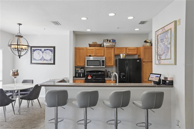 kitchen with an inviting chandelier, decorative light fixtures, black appliances, and a kitchen breakfast bar