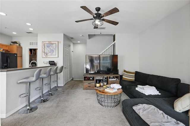 living room featuring sink, light carpet, and ceiling fan