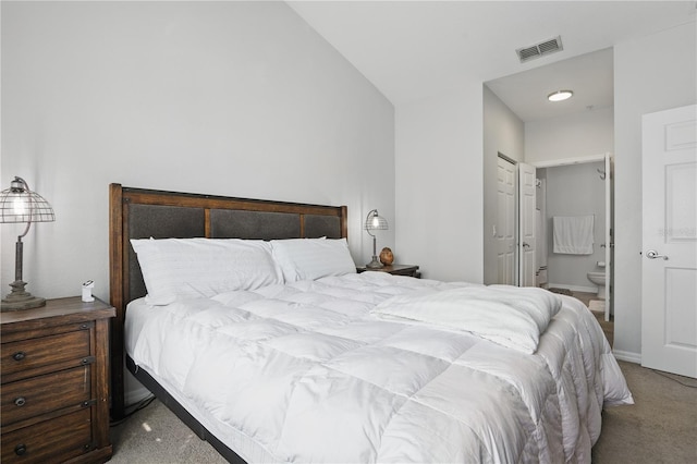 bedroom with lofted ceiling, carpet flooring, and connected bathroom