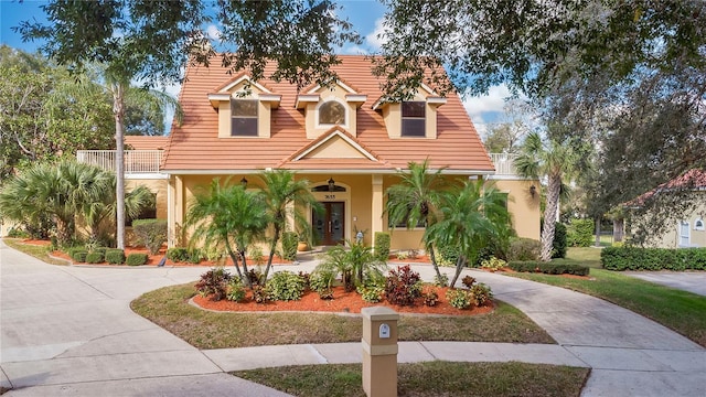 view of front of home featuring driveway, a tile roof, french doors, and stucco siding