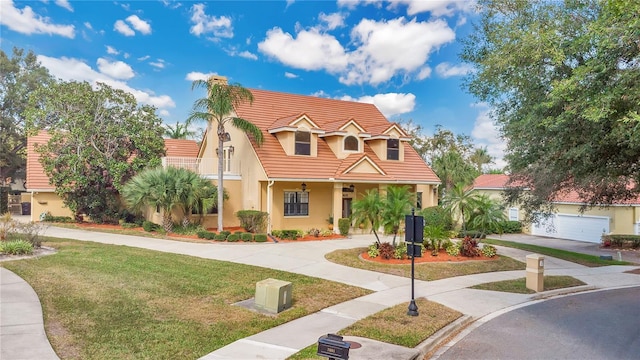 view of front facade featuring a front yard, a tile roof, and stucco siding