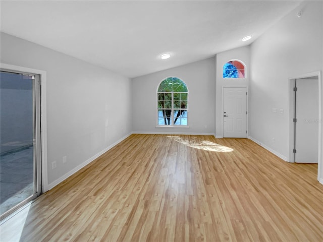 unfurnished living room featuring high vaulted ceiling and light hardwood / wood-style floors