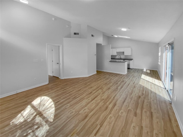 unfurnished living room featuring high vaulted ceiling and light hardwood / wood-style floors