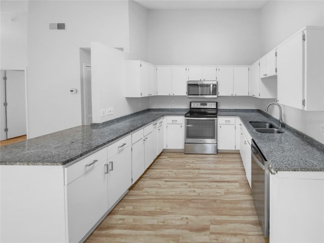 kitchen featuring sink, appliances with stainless steel finishes, white cabinetry, a high ceiling, and light hardwood / wood-style floors