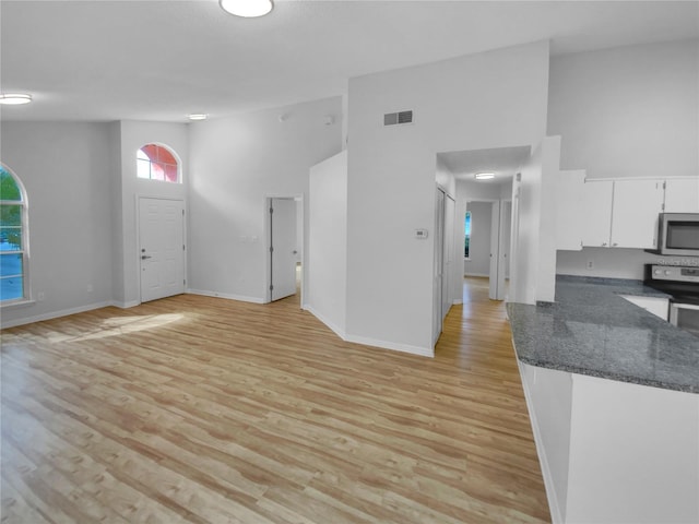 interior space with light hardwood / wood-style flooring, high vaulted ceiling, and appliances with stainless steel finishes