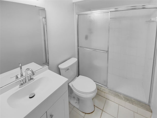 bathroom with tile patterned floors, vanity, toilet, and a shower with door