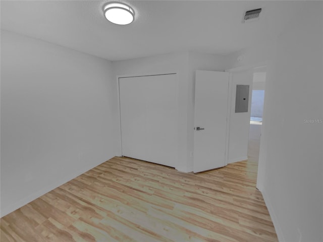 empty room with electric panel and light hardwood / wood-style floors