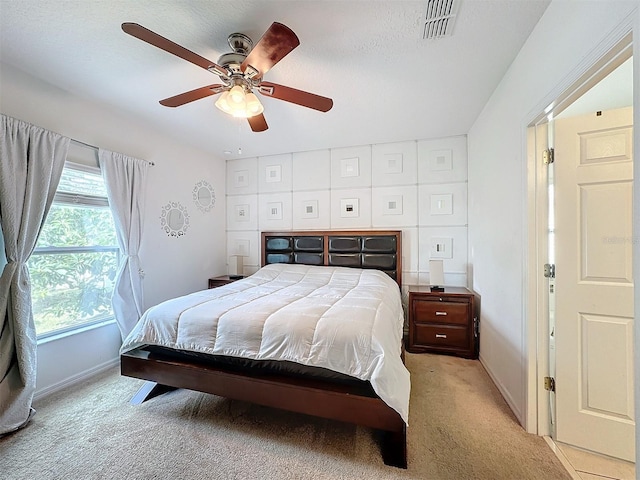 bedroom with light colored carpet, a textured ceiling, and ceiling fan